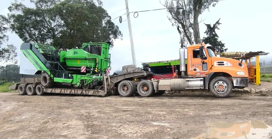 Tractocamión con cama baja transportando maquinaria agrícola